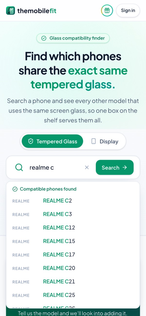 Typing realme c in TheMobileFit's search box suggests Realme phones under Compatible phones found, each opening its glass card.